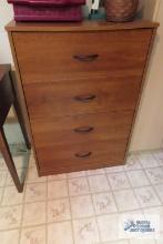 Cherry finish four drawer chest of drawers in basement